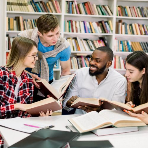 young-multiethnic-friends-two-women-two-men-talking-each-other-smiling-while-reading-books-table-modern-library-campus (1) (1)